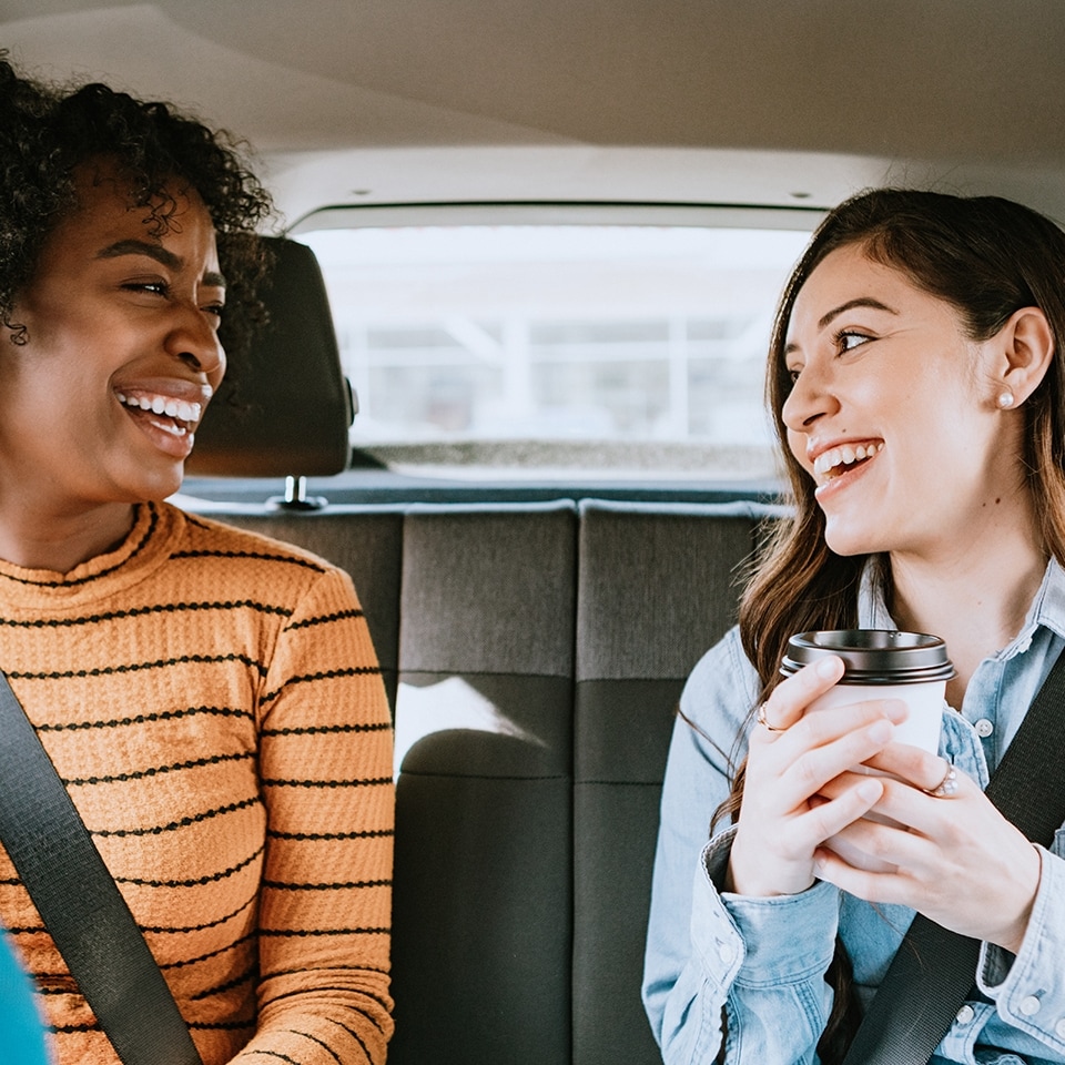 Two friends ride in a crowdsourced taxi, having requested a pick up and drop off on a smartphone.  Shot in Los Angeles, California.